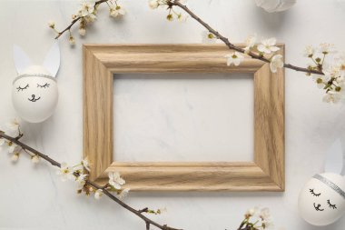 Boş çerçeve, çiçek açan dallar ve beyaz arka planda Paskalya yumurtaları. Üst görünüm