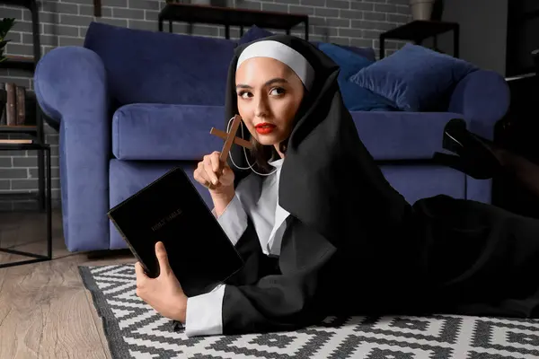 stock image Sexy nun with cross and Holy Bible lying on floor at home