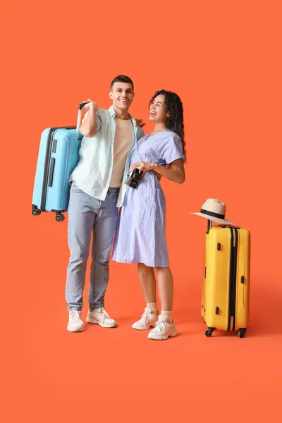 stock image Couple of tourists with suitcases and photo camera on orange background