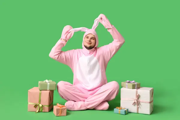 身穿兔子服装 头戴礼品盒的年轻人坐在绿色背景上 复活节庆祝活动 — 图库照片