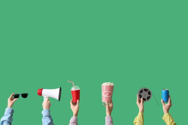 Yeşil arka planda patlamış mısır, içki ve megafonla dolu bir sürü el.