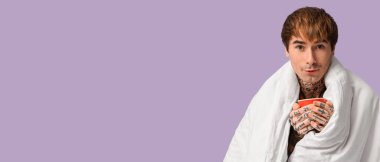 Genç adam battaniye ve çay ile eflatun arkaplan üzerinde metin için yer ile