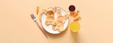 Bej arka planda bir bardak portakal suyu olan komik Paskalya tavşanı krepleri.