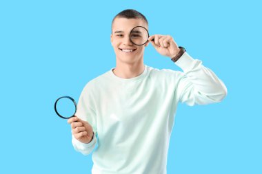Young man with magnifiers  on blue background clipart