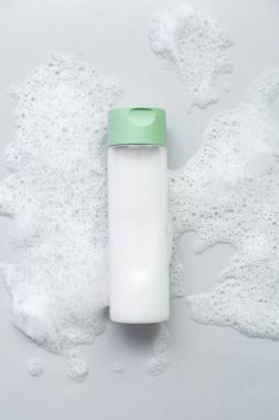 Gri arka planda köpüklü bir şişe kozmetik ürünü.