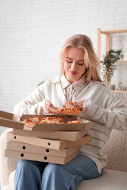 Evde lezzetli pizzalarla dolu kutular tutan genç bir kadın.