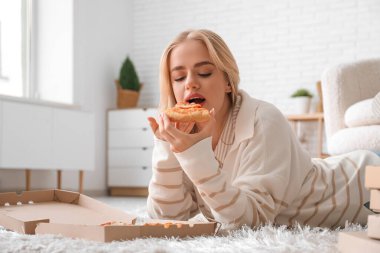 Genç ve güzel bir kadın evde lezzetli pizzalar yiyor.