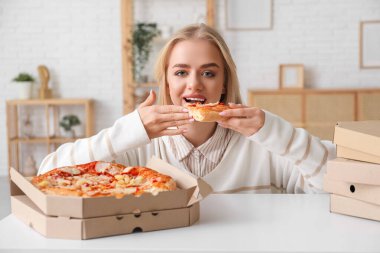 Evde lezzetli pizzalar yiyen çekici bir kadın.
