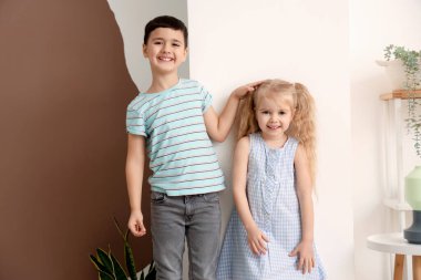 Duvarın yanında boyunu ölçen sevimli küçük çocuklar.