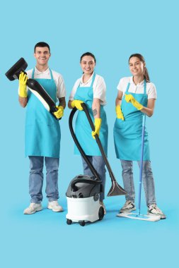 Mavi arka planda malzemeleri olan temizlik işçileri.