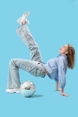 Mavi arka planda disko topu olan güzel, mutlu, stil sahibi bir kadın.