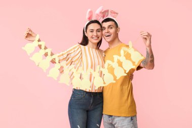 Paskalya tavşanı kulakları ve pembe arka planda çelengi olan mutlu genç çift.