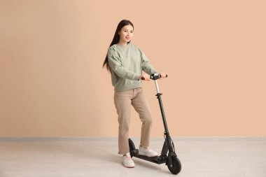 Bej duvarın yanında modern elektrikli scooterlı güzel bir Asyalı kadın.