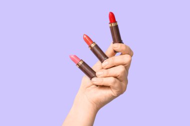 Leylak arka planında farklı ruj izleri olan bir kadın el.