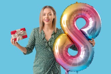 İşitme cihazı olan genç bir kadın balonu 8 şeklinde tutuyor ve mavi arka planda bir hediye. Uluslararası Kadınlar Günü