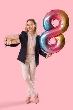 Elinde işitme cihazı olan genç bir kadın ve pembe arka planda 8 şeklinde balon taşıyor. Uluslararası Kadınlar Günü