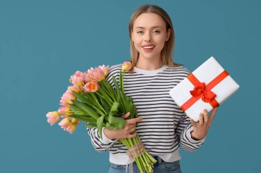 İşitme cihazı olan genç bir kadın mavi arka planda lale ve hediye tutuyor. Uluslararası Kadınlar Günü