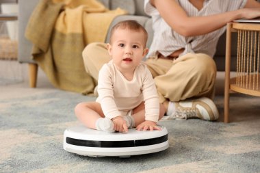 Robot elektrikli süpürgesi olan sevimli bir bebek ve evde annesi, yakın plan.