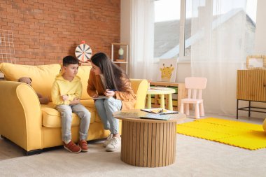 Ofisteki kanepede küçük çocukla çalışan kadın psikolog.