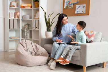 Küçük çocuk ofiste psikologla konuşuyor.