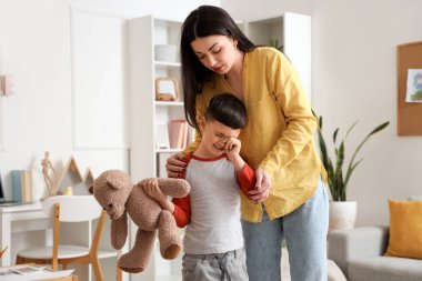 Ofiste oyuncak ayı ve psikologla ağlayan küçük çocuk.
