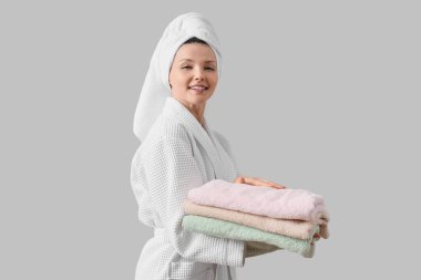 Duştan sonra arka planda temiz havluları olan genç bir kadın.