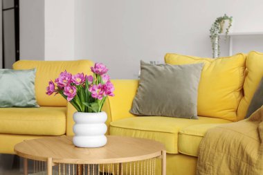 Oturma odasındaki masada pembe laleli vazo.