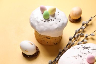 Paskalya pastaları, söğüt dalları ve bej arka planda boyanmış yumurtalar.