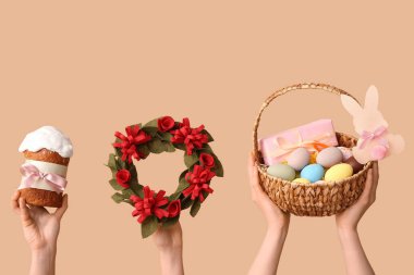 Paskalya pastası tutan kadın elleri, arka planda sepet ve çelenk var.