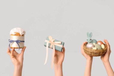 Yumurtalı yuva, paskalya pastası ve beyaz arka planda hediye kutusu olan kadın elleri.