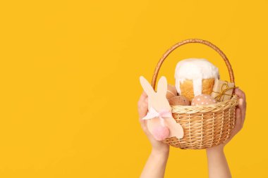 Sarı arka planda Paskalya için sepet tutan kadın.