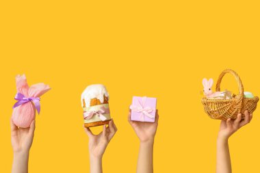 Paskalya pastasını sepetli ve sarı arka planda hediyeli kadın elleri