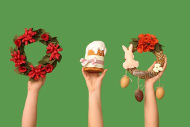 Paskalya pastalı kadın elleri ve yeşil arka planda neşeli çelenkler.