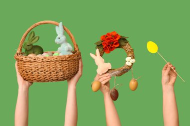 Yeşil arka planda çelenk ve dekorla Paskalya sepetini tutan kadın elleri