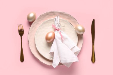 Paskalya yumurtaları ve pembe arka planda çigila çiçekleri olan güzel bir masa.