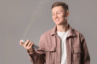 Gri arka planda saç spreyi olan erkek berber.