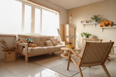 Hafif oturma odasının içinde rüzgar çanı, kanepe ve koltuklar.