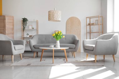 Gri koltuklu modern oturma odası ve laleli vazo.