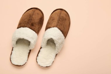 Bej arka planda bir çift kahverengi yumuşak terlik. Üst görünüm