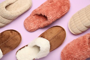 Leylak arka planında üç çift yumuşak terlik. Üst görünüm