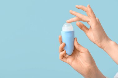 Mavi arka planda deodorantı olan kadın elleri