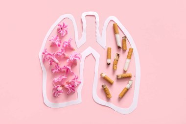 Çiçekli kağıt ciğerler ve pembe arka planda sigara izmaritleri. Sigara içmeyi bırak.