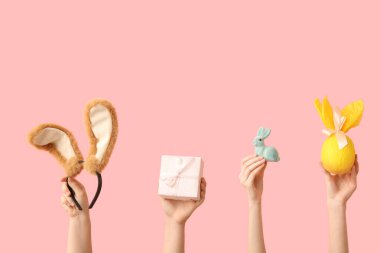 Tavşanlı kadın elleri, pembe arka planda hediye yumurtası ve kulaklık.