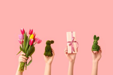 Hediyeli kadın elleri, pembe arka planda tavşanlar ve bir buket lale.