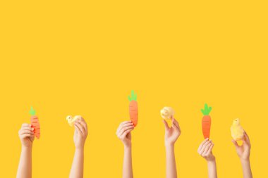 Hatunları olan kadın eller ve sarı arka planda kağıt havuç. Paskalya konsepti.