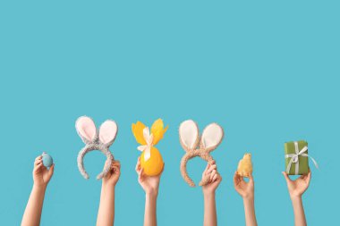 Hatunla kadın eli, tavşan kulaklığı, boyanmış yumurta ve mavi arka planda hediye. Paskalya konsepti.