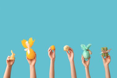 Hediye yumurtalı kadın eller, civciv, tavşan ve mavi arka planda Paskalya yumurtası.