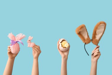 Tavşan, piliç, saç bandı ve mavi arka planda hediye yumurtası olan kadın elleri. Paskalya konsepti.