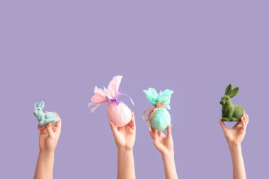 Hediye yumurtalı kadın elleri ve menekşe arka planda Paskalya tavşanları.