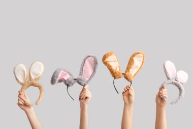 Paskalya tavşanı kulaklıklı, gri arka planda kadın eli.